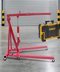 Premium Heavy Duty 1 Ton Folding Hydraulic Engine Hoist Shop Crane With Wheels lifting a DEWALT tool case in a garage.