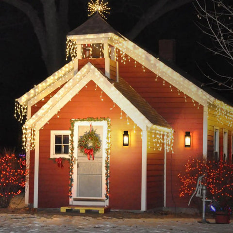 Red house with Christmas lights and wreath, featuring Dope Outdoor Wall Light Fixture With Clear Glass Shade on the porch.