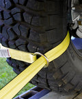 Close-up of vehicle tire secured with Four Pack 2 Inch By 96 Inch Tie Down Straps Kit With J Hook Ratchets And Wear Pads For Cars SUVs Jeeps