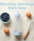 All In One Pancake Batter Dispenser with BlenderBall next to whisk, eggs, flour, and blueberries