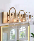 3 Light Modern Vanity Light Fixture in Brass Finish With Clear Glass Shades For Bathroom, mounted on wall above mirror