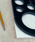 Top Shelf 11 Piece Phenolic Corner Radius And Circle Template Set showing circle templates on wood with a pencil for woodworking.