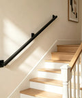 Six Foot Wall Mounted Stair Handrail Rock Solid Heavy Duty Safety Grab Bar Built Crazy Sturdy With Thick Steel Supporting Over 500 Pounds Zero Wobble Action For Seniors And Kids mounted on a wall beside wooden stairs.