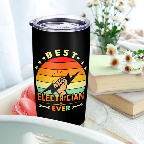 Electrician Gift For Men 20oz Travel Coffee Tumbler Mug With Meaningful Script on table with books and flowers