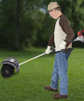Gas Powered Handheld Sweeper Broom For Lawn Cleanup 52cc 2 Stroke Engine Two Point Three HP Portable Gasoline Powered Sweeping Machine With Fuel Tank Built To Last Durable ABS Aluminum Build Easy Start And Debris Removal, side view on grass