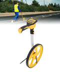 Heavy Duty Digital Measuring Wheel For Yard And Job Sites Folding Telescopic Handle With Backlit Screen And Carry Pouch Measures Up To 100K Feet, shown measuring on a road.