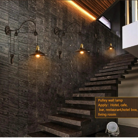 Dope Vintage Wall Sconce Featuring Classic Wrought Iron Build With Handsome Pulley Adjustment For Slick Loft Rooms And Chill Bar Decor That Seriously Slays And Looks Absolutely Lit on a stone wall next to stairs.
