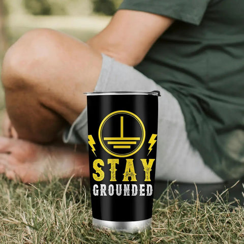 Electrical Engineer Gift Tumbler 20oz Stainless Steel With Lid And Straw, black with 'Stay Grounded' design, on grass.
