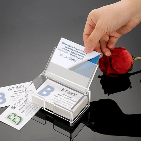 Hand placing card in Clear Acrylic Business Card Holder With Display Lid on black countertop