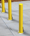 4X36 Inch Badass Removable Bollard With Embedment Sleeve Powder Coated Yellow Carbon Steel installed on concrete surface.