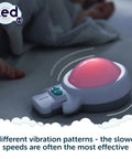 Calming Baby Sleep Aid With 6 Soothing Vibration Modes And Red Night Light on mattress, shown next to sleeping infant hand.