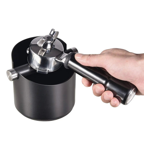 Hand using Espresso Knock Box For Home Barista Use Black Stainless Steel Coffee Ground Catcher With Removable Knock Bar