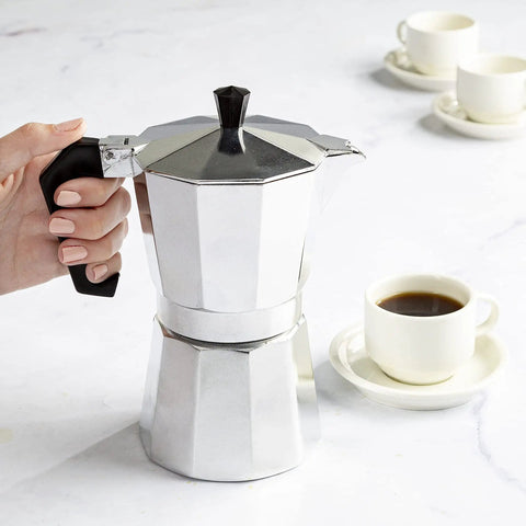 Person using Stovetop Moka Pot Espresso Maker For Home Brew 6 Cup Greca Style Coffee Pot For Italian And Cuban Cafe Perfect For Lattes Cappuccinos Americanos Quick Rich Brews In Silver on a countertop