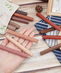 Premium Grade Wood Pen Blanks And Dowel Rods 12 Assorted Colors Half Inch By Four Inch Turning Blocks on palm, assorted colors laid out.