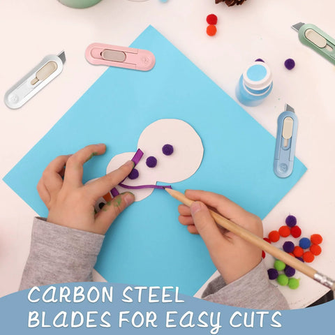 Overhead view of four Amazon PSC Box Cutters in pastel colors around a paper craft, cutting purple felt on blue paper.