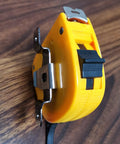 Close-up of Badass Rock Solid Metal Tape Measure Holder Belt Clip and Pocket Tool Holster with secure rivets, yellow and black.