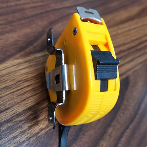Close-up of Badass Rock Solid Metal Tape Measure Holder Belt Clip and Pocket Tool Holster with secure rivets, yellow and black.