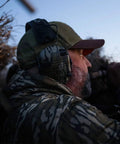 Man wearing Razor Slim Patriot Series Ear Muffs with Ultra Low Profile Yet Powerful Hearing Protection in olive drab for outdoors