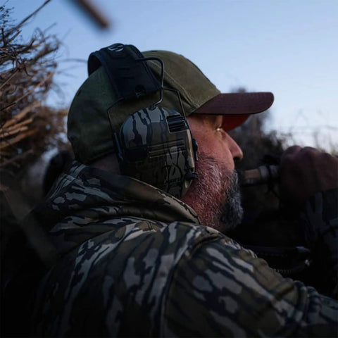 Man wearing Razor Slim Patriot Series Ear Muffs with Ultra Low Profile Yet Powerful Hearing Protection in olive drab for outdoors