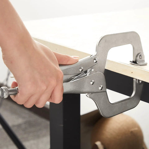 Person using Four Piece Locking C Clamp Set With Fixed And Swivel Pads, 6 Inch Dual Pad, 9 Inch And 11 Inch Welding Clamps on a table