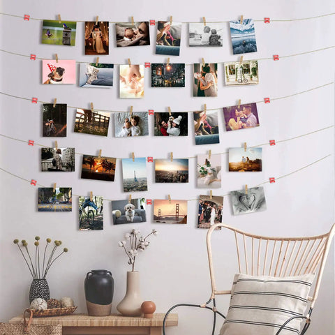 Photos hanging on string with clothespins on wall above decorative shelf and chair.