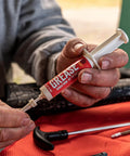Close-up of hands using 10cc syringe All Weather Synthetic Grease For Firearms High Tech Lubricant That Clings In Extreme Heat Or Cold