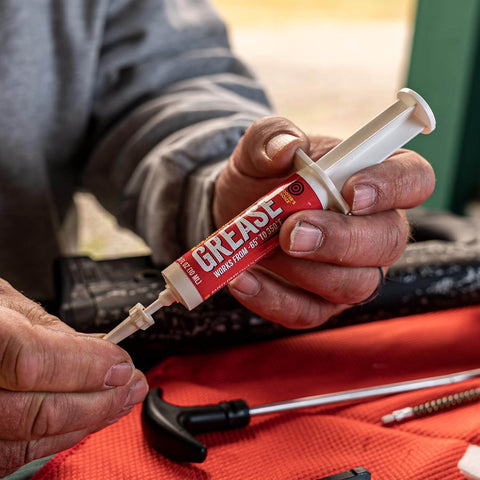 Close-up of hands using 10cc syringe All Weather Synthetic Grease For Firearms High Tech Lubricant That Clings In Extreme Heat Or Cold