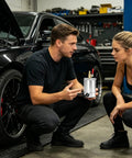 Two people discussing the Heavy Duty 300ml Oil Catch Can Kit With Double Port Design, showcasing the product in an automotive workshop.