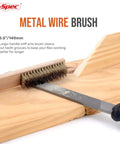 Metal wire brush cleaning grooves on a wooden board, close-up view of brush and handle for file maintenance.