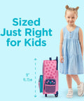 Front view of pink Stephen Joseph kids rolling luggage with flower pattern and teal pockets beside a girl in a blue dress
