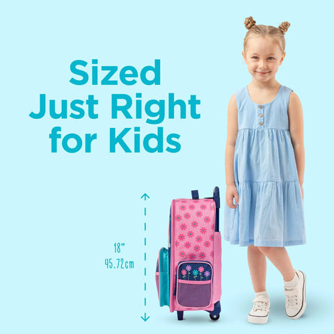 Front view of pink Stephen Joseph kids rolling luggage with flower pattern and teal pockets beside a girl in a blue dress