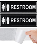 Two Pack Unisex Bathroom Signs For Doors Or Walls, Heavy Duty Metal Signs With Super Strong Adhesive, Easy Install For Home, Office Or Business Use, Black 9 Inch By 3 Inch, shown with adhesive backing.