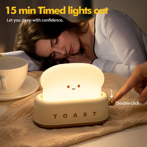 Close-up of Toaster Shaped LED Table Lamp With Rechargeable Battery Nightstand Light, glowing on bedside next to sleeping woman.