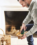 Man using Wood Moisture Meter With Pin Probes, Fast Reading For DIYers And Pros, near fireplace with wood logs