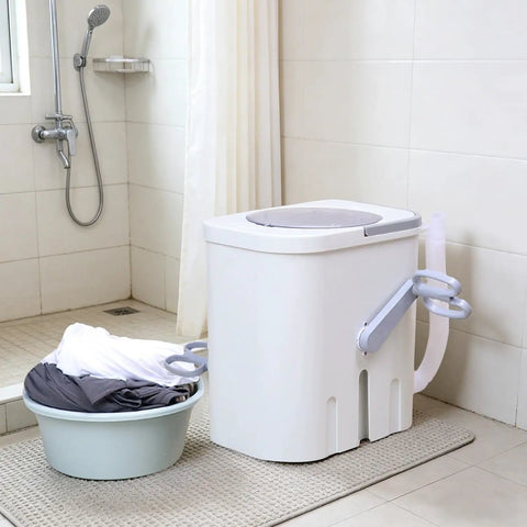 Hand Crank Washing Machine With Biomimetic Scrub Interior Manual Portable Laundry Soaker placed beside a basin of clothes in a bathroom.