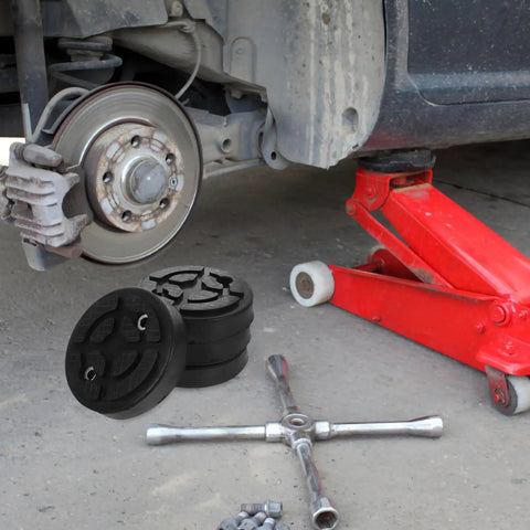 Vosarea Heavy Duty Car Lift Pads Set Of Four Round Auto Jacking Rubber Mats for Two Post Hoist on garage floor with tools and vehicle.