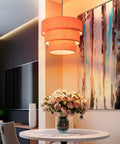 Orange Plug In Pendant Light With Three Tier Mid Century Modern Linen Shades hanging above a dining table with flowers.