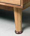 Light brown Felt Chair Leg Pads And Caster Cups Set For Hardwood Floors on wooden furniture leg, protecting against scratches.