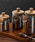 Go Ahead And Upgrade Your Countertop Setup With This Solid Clear Glass Storage Jar Featuring An Airtight Sealed Kitchen Canister And Wooden Spoon For Coffee Beans 900Ml Capacity Handles Dry Goods Smoothly And Looks Dope, displaying three jars with wooden lids and spoons on a wooden tray.