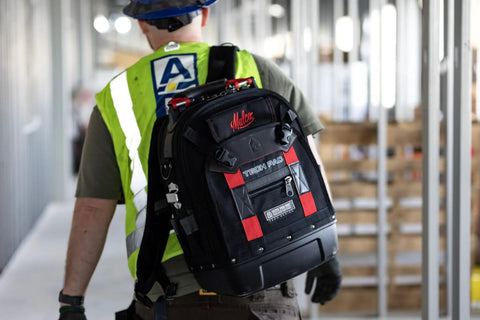 Worker carrying HVAC Pro Kit 32 Piece Service Installation And Fabrication Set with VETO Tech Pac Backpack on construction site