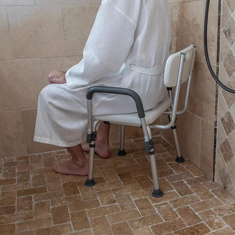 Person sitting on adjustable white bath and shower chair with depth adjustable back, 300 lb capacity, senior safe shower seat.