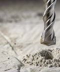 Sabre Tools SDS Plus drill bit close-up, carbide-tipped, cutting into concrete dust