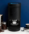 Automatic Coffee Tamper Machine With Adjustable Electrical Pressure Control For 58Mm Portafilters on a countertop with coffee tools.
