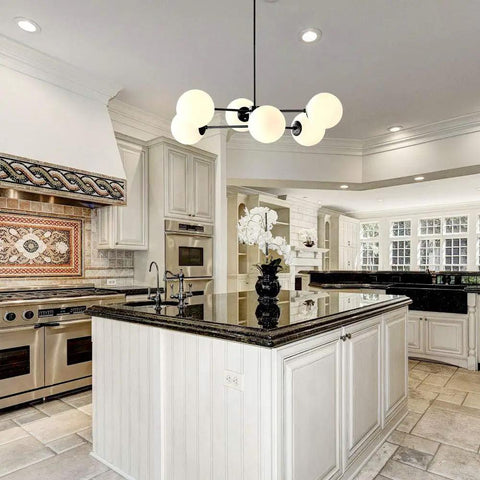 Six Light Sputnik Chandelier In Matte Black With Globe Glass Shades hanging over kitchen island in modern dining area.
