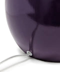 Close-up of the curved eggplant purple ceramic base of the table lamp with visible cord.