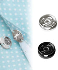 Close-up of 120 Set Sew-On Metal Snap Buttons Pack With 8mm And 10mm Sizes In Black And Silver on fabric