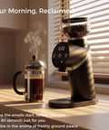 Talia Electric Coffee Grinder With 48Mm Titanium Plated Conical Burrs For Uniform Grinds beside a steaming French press.