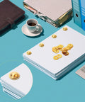 Gold Brass Washers And Paper Brads 500 Piece Set For Paper Crafts Scrapbooking And DIY Projects 15mm Outer Diameter 3mm Inner Diameter Metal Fasteners With Storage Box Included on a desk with folders and coffee cup