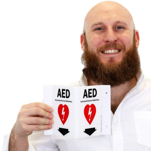 Man holding Two Sided Acrylic Aed Sign Built Hard As Nails To Help You Locate Life Saving Gear Fast With Heavy Duty Polished Wall Mount Display Featuring Bold Down Arrow Symbol Indoors Outdoors.