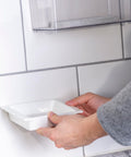 Person using Max Strength Construction Adhesive Crystal Clear Two And A Half Ounce Squeeze Tube Waterproof Gap Filling on a tile wall.